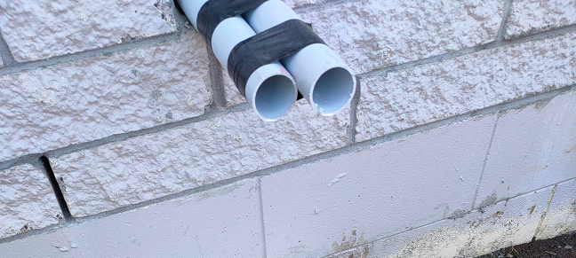 Plumbing and drainage pipes emerging from a residential building.