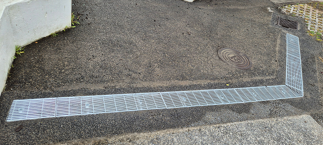 Driveway drainage channel installed to direct rainwater away from paved areas.